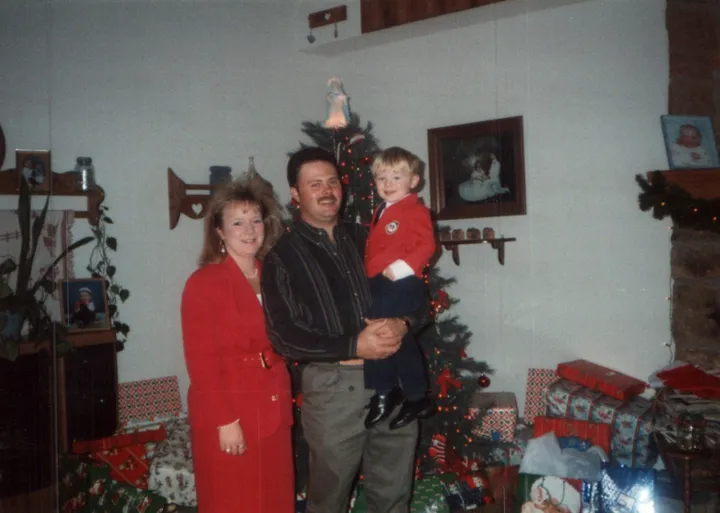 Brian and Angie King holding a young Ryan in front of a Christmas tree