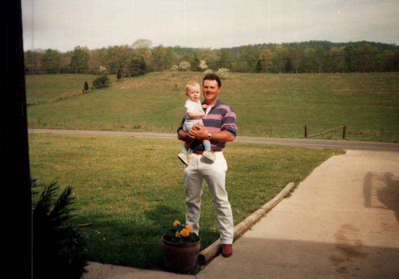 Brian King holding baby Ryan in front of a field in Union Valley