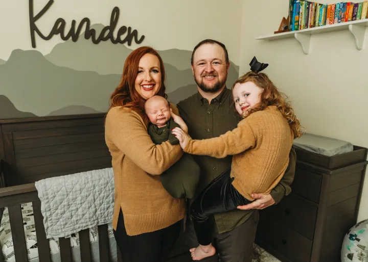 Brittany holding newborn Kamden while Ryan holds Kinsley in the nursery