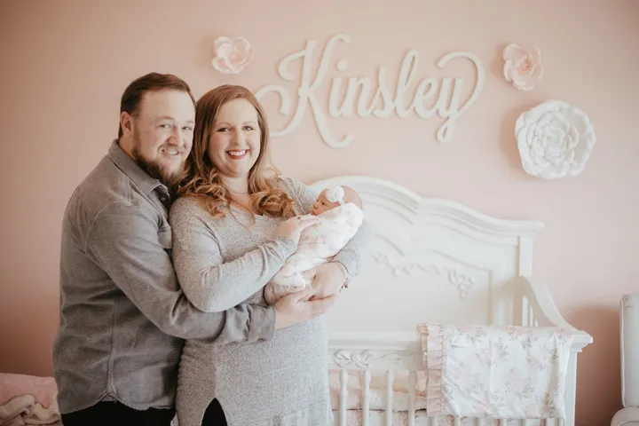 Ryan and Brittany holding newborn Kinsley in her nursery