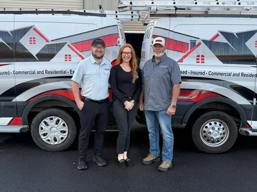 Ryan, Brittany and Brian King standing in front of two Brian King Roofing vans