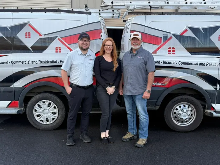 Ryan, Brittany and Brian King in front of two Brian King Roofing vans