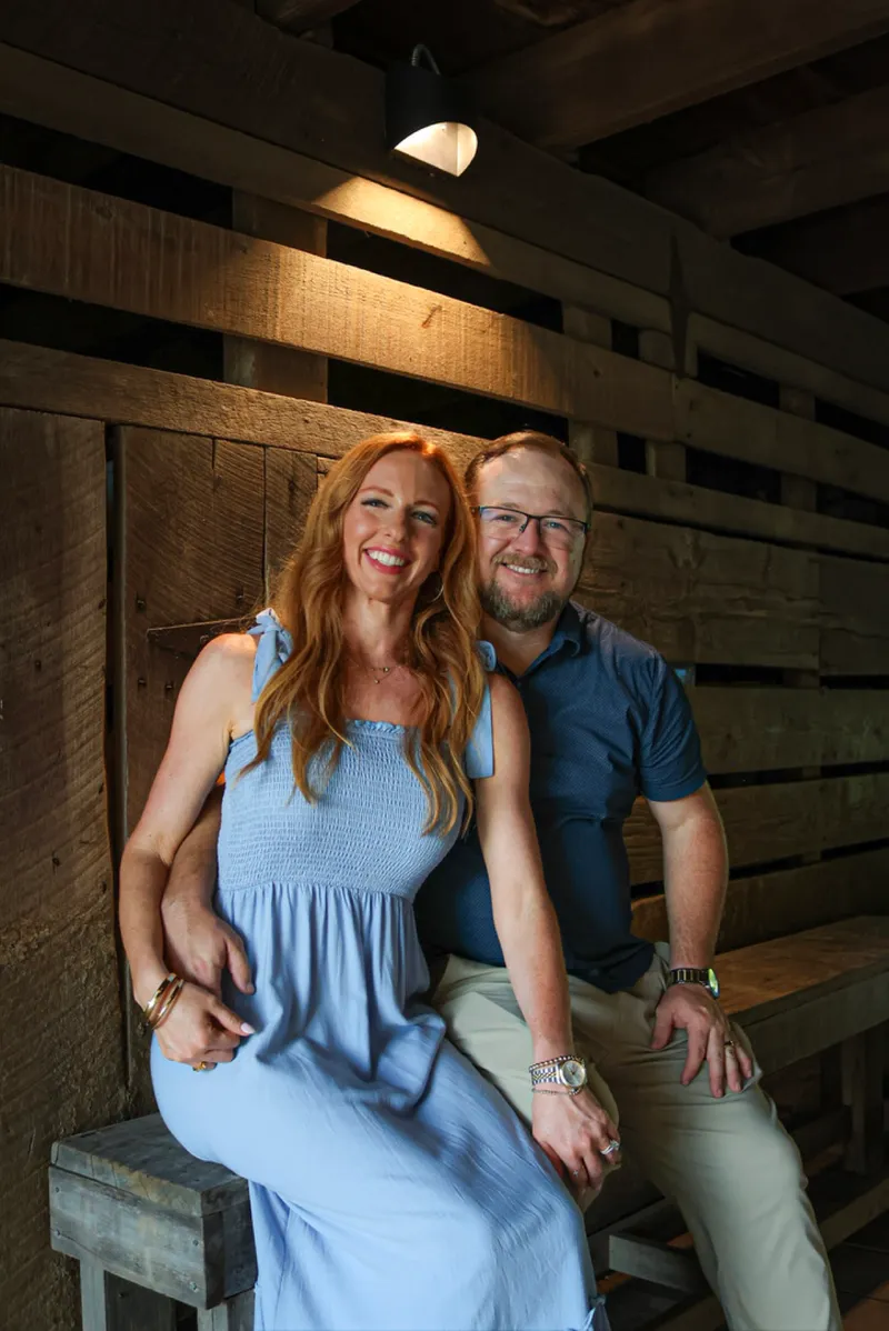 Ryan and Brittany sitting together on a wooden bench inside a barn