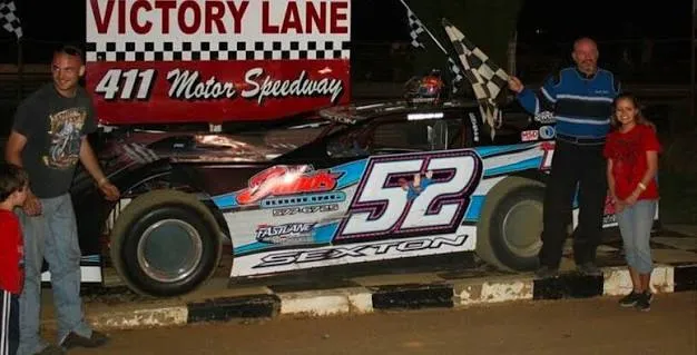 Scott Sexton's black and blue #52 late model in victory lane at 411 Motor Speedway, with Scott waving the checkered flag