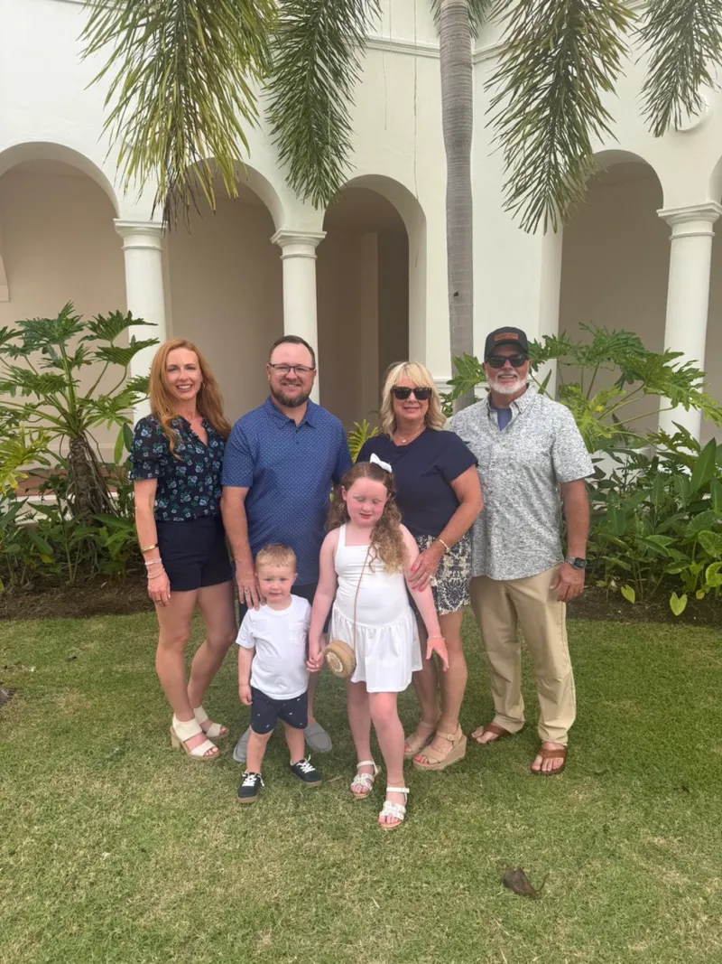 Ryan, Brittany, the kids and Ryan's parents in front of a white resort building with palm trees