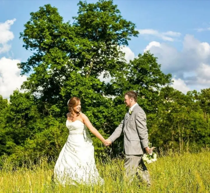 Ryan and Brittany walking hand in hand through a field on their wedding day